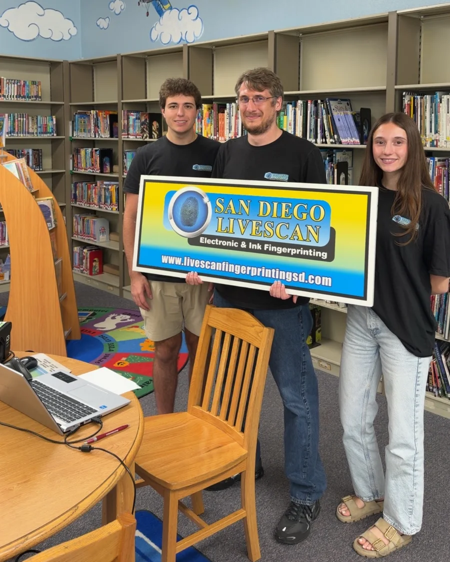 The San Diego Livescan mobile team holding the company sign at a school library event